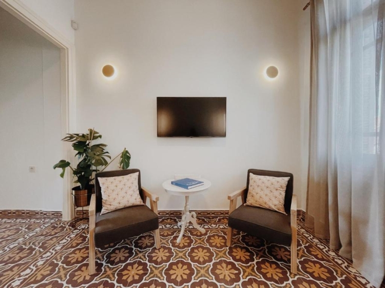 Sala de estar, sillas, televisor, luces de pared, azulejos decorativos Kale Kapi City Living Apartamentos en Xania